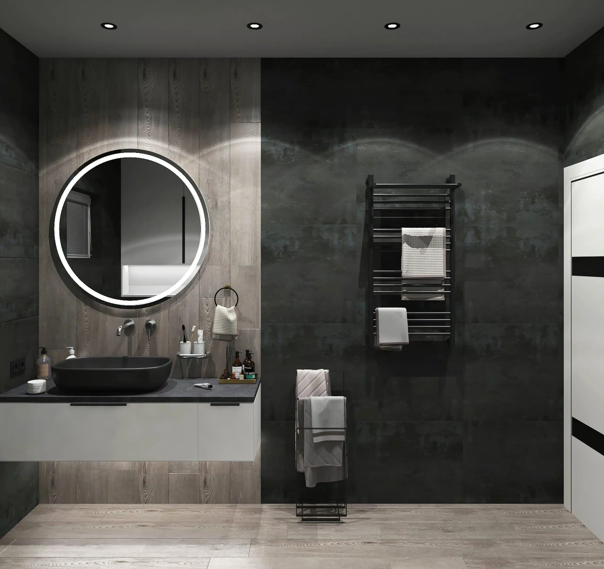 Contemporary bathroom with a round LED backlit mirror above a floating vanity unit, featuring a matte black countertop basin and wall-mounted taps. The space includes a black heated towel rail on a dark feature wall and a freestanding towel rack on light wood flooring